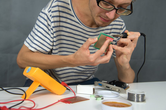 Young man use iron soldering electric parts