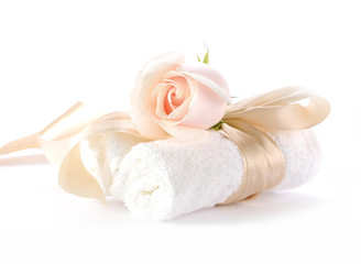 Fototapeta na wymiar Rose with decorative ribbons over Rolled up Bath Towels