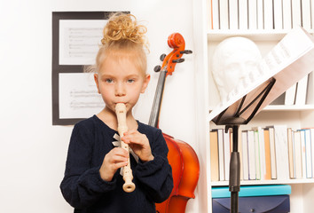 Blond curly girl plays flute standing near cello © Sergey Novikov