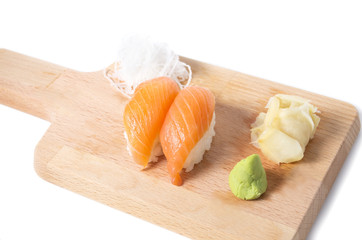 Japanese salmon sushi on a wooden cutting board with ginger and