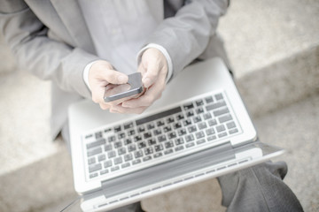 Businessman using laptop pc and mobile phone. He is sitting on a