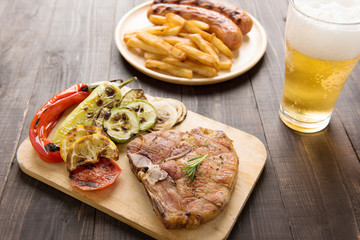 Grilled Steak with salad and beer and french fries sausage