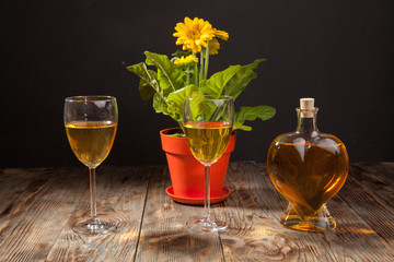 A bottle of white wine with glasses and a flower