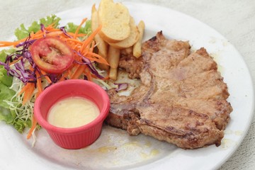 steaks and vegetable salad with french fries.