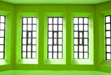 Abstract view of symmetrical windows on green wall