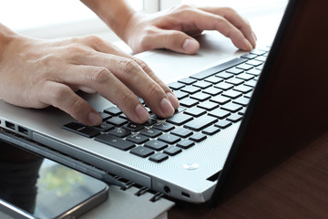 Close up of business man hand working on  laptop computer on woo