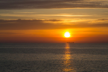 Naklejka na ściany i meble Sunset at sea with boat on the horizon