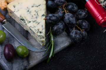 Marble board with cheese selection, wine and grapes