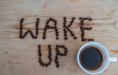 Cup of coffee on wooden background and wake up coffee beans