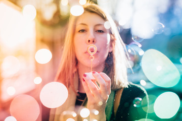 Portrait of young woman blowing soap bubbles