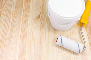 paint roller with paint can on wooden background