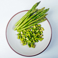 Fresh, washed asparagus in white bowl.