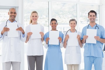 Team of smiling doctors looking at camera and holding paper