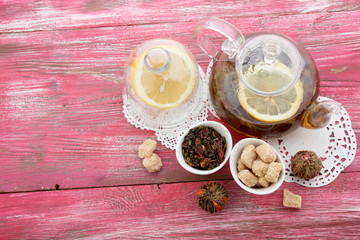 Ripe lemon, cinnamon and fruit drink in glass teapot on wooden