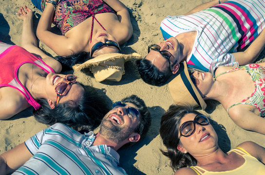 gruppo di amici prendono il sole stesi sulla sabbia