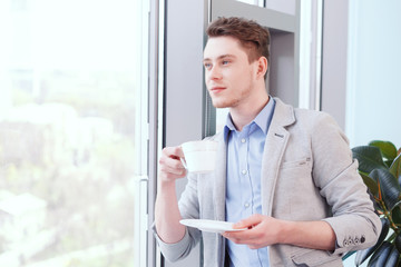 Naklejka na ściany i meble Young handsome man with coffee in office