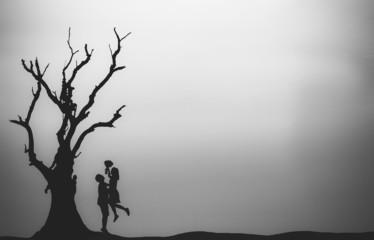 Silhouette of couple in love with tree at sunset.