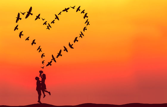 Silhouette of couple in love with heart shaped made by flying bi