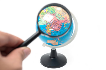 hand holding magnifying glass over earth globe