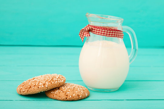 Jug of milk with cookies on blue wooden kitchen. Selective focus