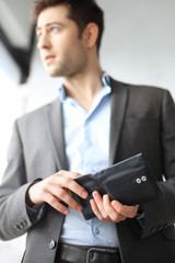 Portfel.Mężczyzna w garniturze trzyma w dłoni portfel
