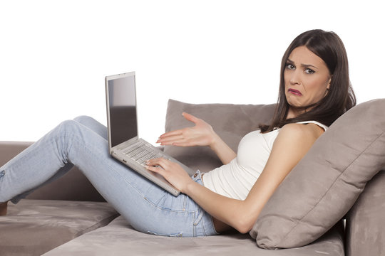 young woman lying on the couch and complained to her laptop