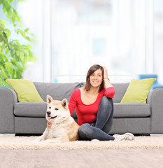 Woman seated on the floor at home, with her dog