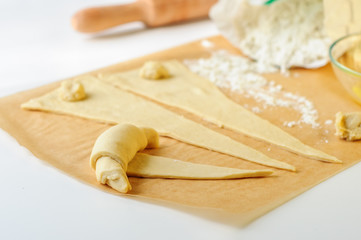 Croissants cooking on white table with flour and baking paper