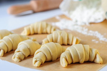 Croissants cooking on white table with flour and baking paper