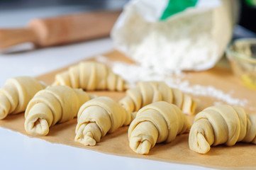 Croissants cooking on white table with flour and baking paper