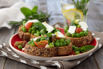 Green peas with cherry tomatoes, feta cheese and mint on toast