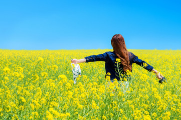 Young woman standing in yellow rapeseed field.