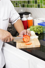 Chef's hands cutting Tomato