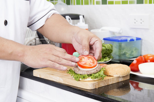 Chef putting slice of tomato on the Hamburger bun