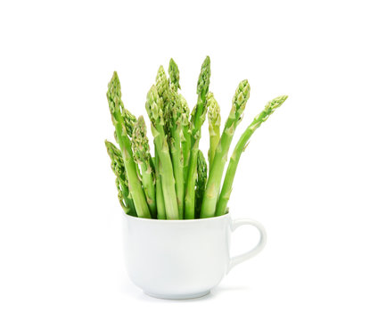 Asparagus arrange in a white cup on white background