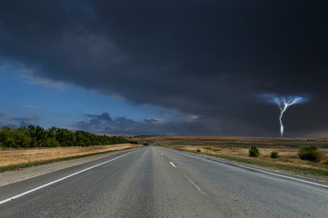 Fototapeta premium Road under stormy clouds with lightning