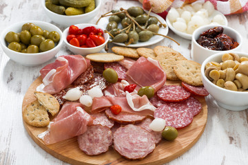 Assorted meat snacks, sausages and pickles on wooden board