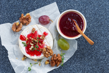 Camembert with berry jam, fresh grapes and nuts, top view