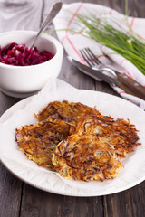 Potato fritters, beet salad, green onions on a wooden surface