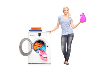 Woman holding detergent next to a washing machine