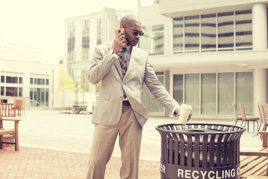 Man throwing empty paper coffee cup in recycling bin