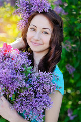 Beautiful woman holding a bouquet of lilacs in spring park