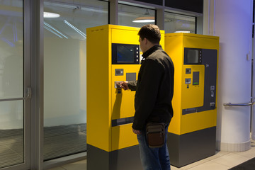 man pays parking in parking machine in the mall