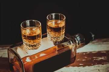 two glasses of whiskey are on the bottle with alcohol