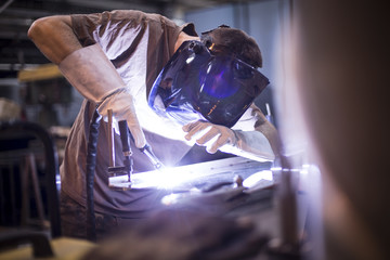 Employee welding stainless steel using welder machine