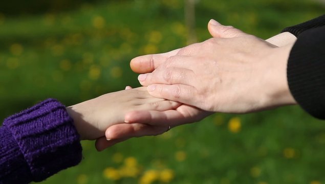 mom's hand gently stroking her daughter's hand