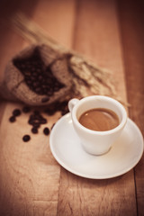 Hot coffee and coffee beans on a wooden table with vintage tone.
