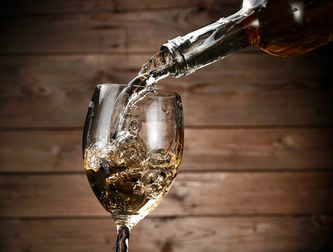 White wine pouring on wood background