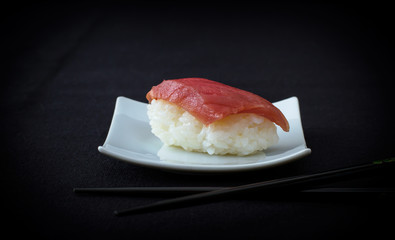 nigiri tuna sushi with chopstick on black