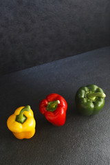 Three bell peppers on Indian Limestone surface.